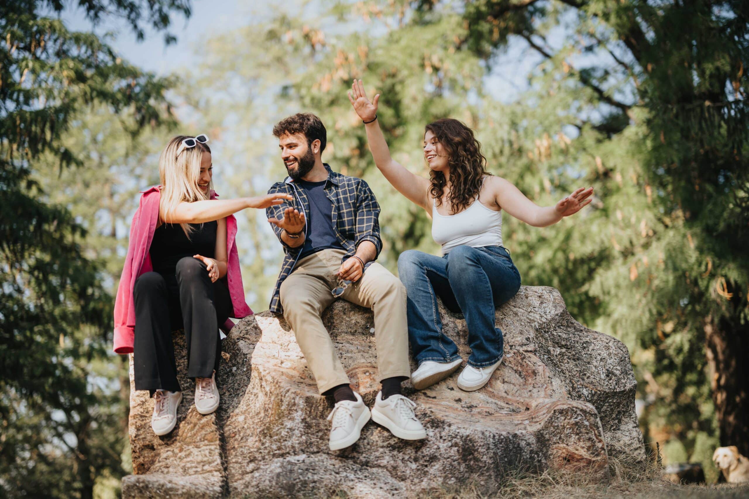Three OCD patients sitting on a rock outside laughing.