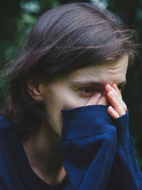 Person with their hand on their face, looking reflective