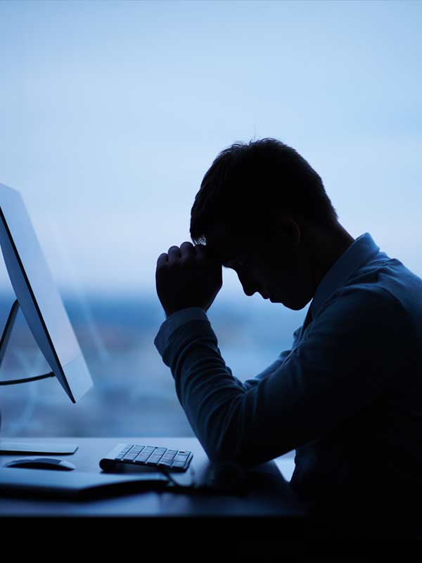 Silhouette of a man at work stresses as it's late at tnight.